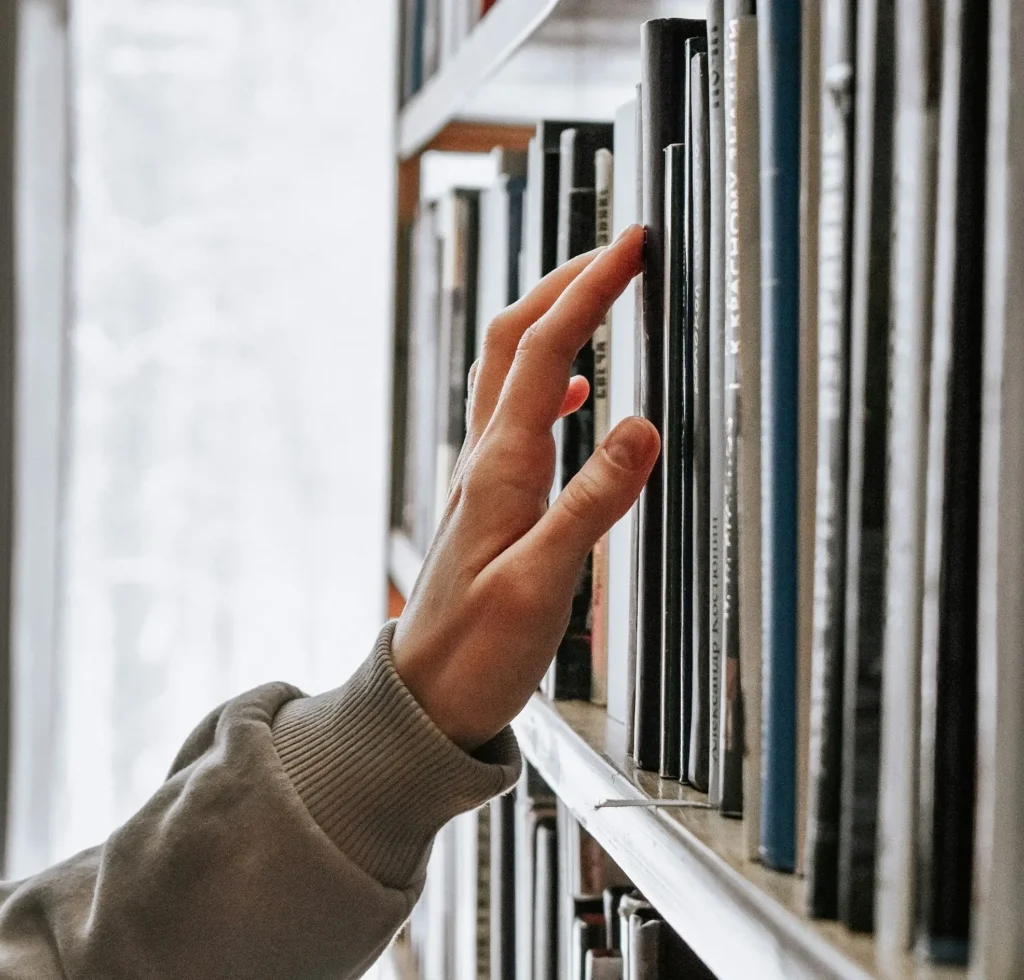A person's hand as they browse library books
