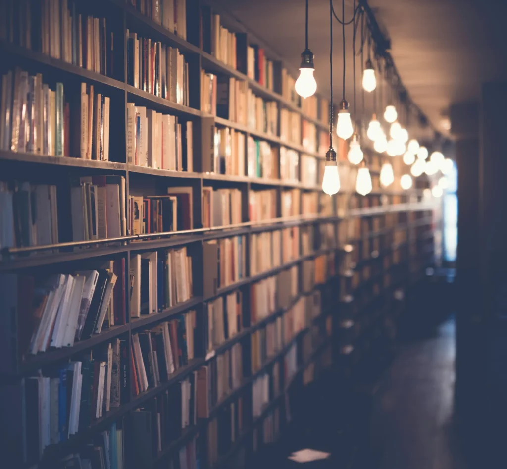 A row of library book stacks with lightbulbs hanging down from the ceiling